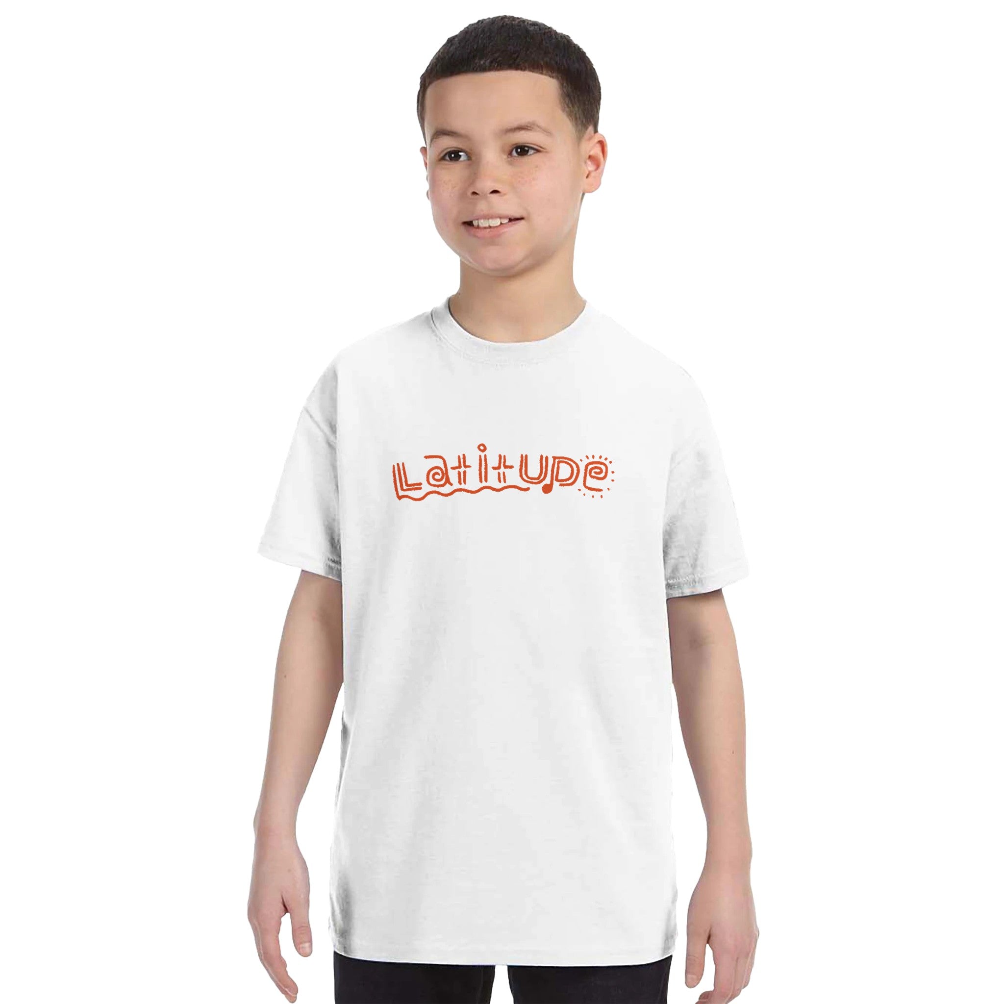A smiling boy models the Latitude Kids 2024 Line Up White T-Shirt from Latitude Festival Store, featuring playful orange Latitude text across the chest, perfect for childrens casual wear on a plain white background.