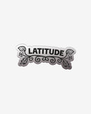The Pin Badge by 2025 features the word LATITUDE in bold black letters, accented with ornate swirls and leaf designs around the text, set against a white background.