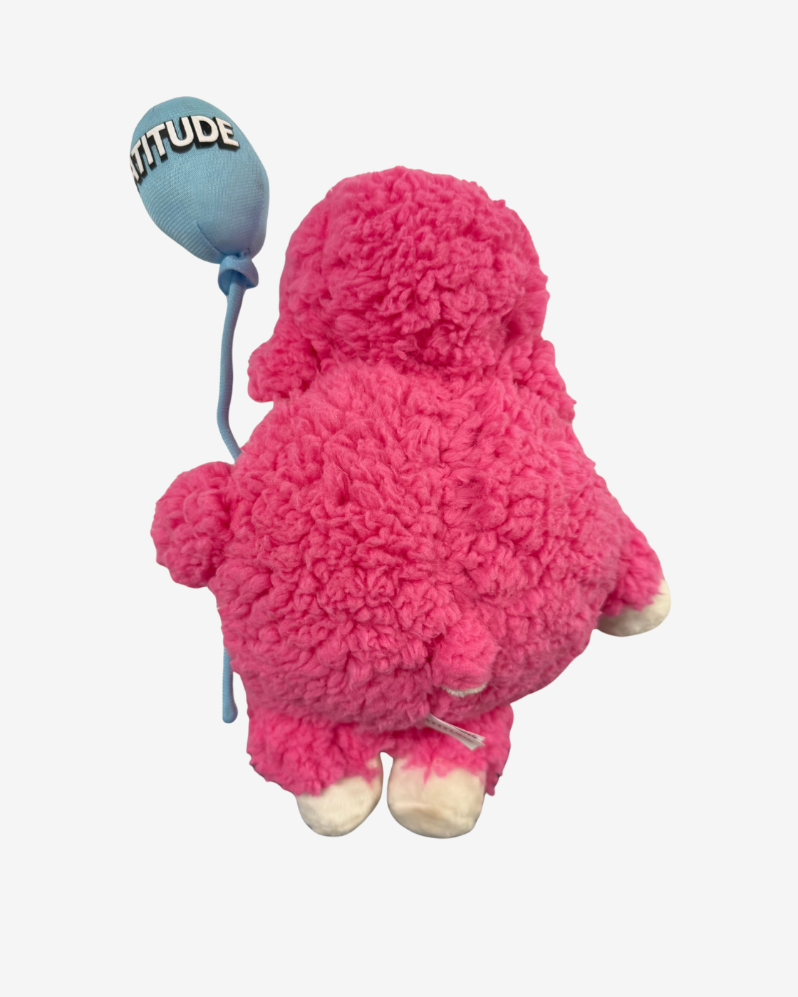 The Latitude Plush With Balloon from Latitude Festival 2026 features a soft, fluffy pink toy with white feet, shown from behind as it holds a blue festival balloon reading “ATTITUDE.” Set against a plain background, this cuddly keepsake captures the lively spirit and positive vibes of the festival.